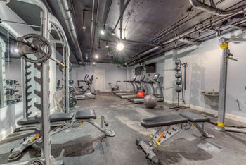 A gym with a variety of equipment including weights and benches.